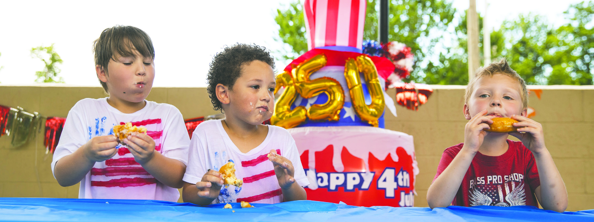Young competitors race to finish their treats during the doughnut eating contest against the Crescent Police Department at the annual Crescent Glory Days Fourth of July celebration on July 4. Photo by Brent Fuchs