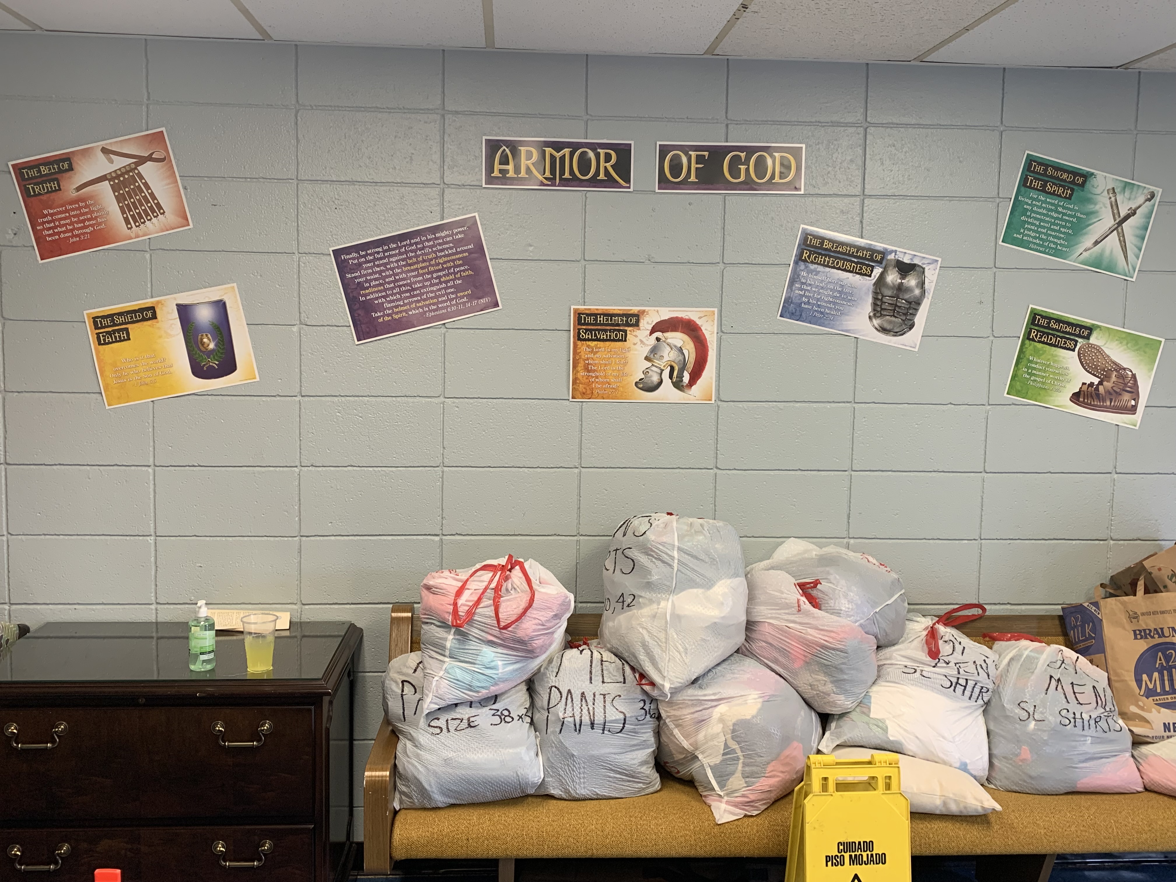 Donated items along the wall include clothes, sanitary kits, and cots.