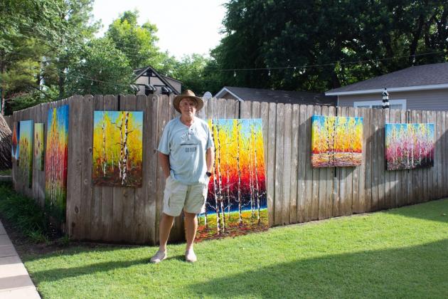 Tim Kenney, photo of artist displaying artwork on fence during OK Art Crawl 2020