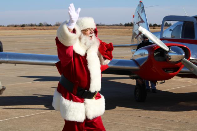Santa waving to crowd after exiting plane.