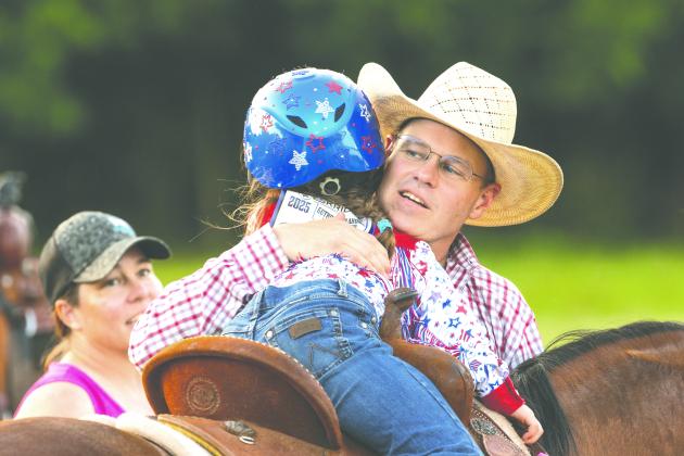 Margaret Boulter of Minco gets a hug from her father, Blaine, before competing in the pole bending event at the Guthrie Youth Rodeo on Saturday at the Logan County Fairgrounds.