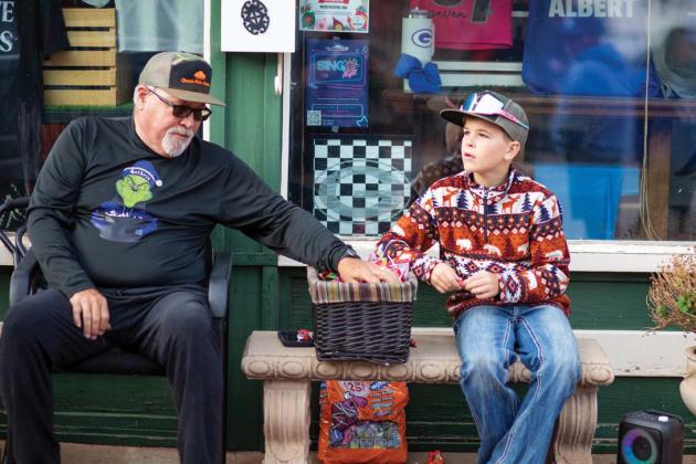 Grandfather and grandson team up to hand out candy to excited trick-or-treaters during Guthrie’s downtown Halloween festivities.