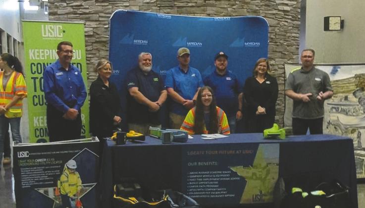 Owen Mallow signs his employment contract with USIC on April 15, 2026, at Meridian Technology Center during a ceremony attended by family, friends and company representatives. Mallow and classmates also received their assigned work vehicles following the signing. Photo submitted