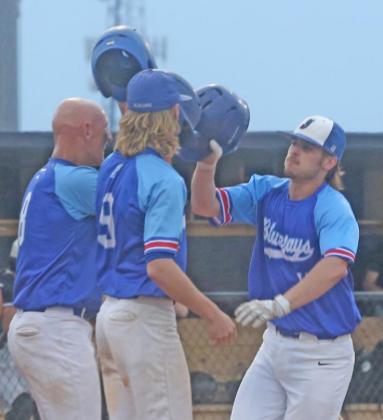 Josh Rains and Cole Whitfield greet Peyton Miller after scoring on his home run