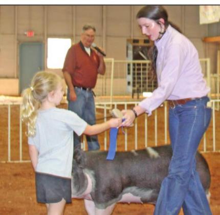Baylee Brown recieves Grand Champion ribbon from Claire Brown at livestock show on Saturday