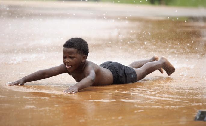 A child slides through the spray at Banner Park’s splash pad in Guthrie. Photo by Brent Fuchs