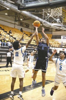 Addison Long (23) of Guthrie goes up for a layup between Del City defenders during a regional game Feb. 27 at Del City High School. Photo by Brent Fuchs