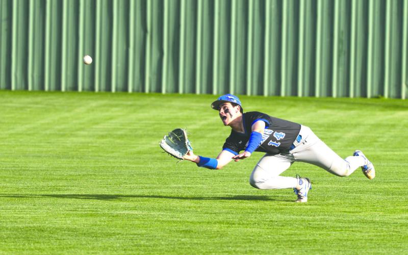 Guthrie’s Hayden Clymer (14) dives for a ball in right field Friday, March 13, 2026, at Bishop McGuinness High School. Guthrie defeated Bishop McGuinness 8-5.