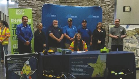 Owen Mallow signs his employment contract with USIC on April 15, 2026, at Meridian Technology Center during a ceremony attended by family, friends and company representatives. Mallow and classmates also received their assigned work vehicles following the signing. Photo submitted
