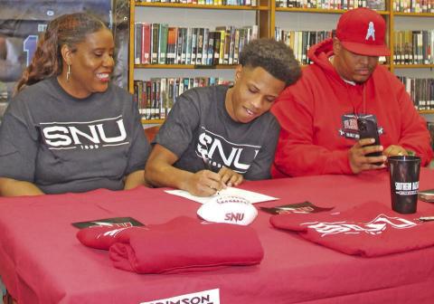 LEFT: Jaylen Chelf signs Letter of Intent with Southern Nazarene University as Jacqueline chelf and Harold Fields look on. Photo by Mike Monahan