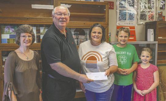 Central District four Trustee, Sid Sperry, presents 4-H Robotics Club leader Jennifer Dejonge; robotics club member Patrick Reinert, cloverbud member Jacqueline Reinert, and FCS/4H Educator Dawn Andrew with a grant from the Central Community Foundation.