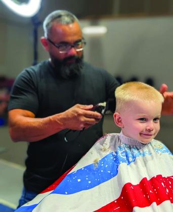 Paul Ambriz of The Grand Ol’ Barbershop gives a student a haircut during the Back to School Bash, helping local students look their best for the start of the school year. Photo courtesy of Guthrie Chamber of Commerce.