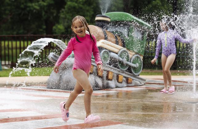 A child laughs while playing in the splash pad at Mineral Wells Park in Guthrie. Photo by Brent Fuchs