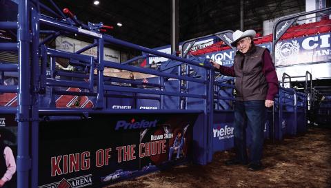 Delmer Smith stands in front of the commemorative chute named in his honor at Lazy E Arena. Smith, known as the “King of the Chutes,” has worked at the arena for 41 years. Photo courtesy of Lazy E Arena.