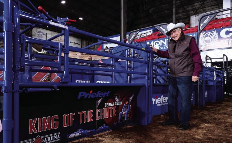Delmer Smith stands in front of the commemorative chute named in his honor at Lazy E Arena. Smith, known as the “King of the Chutes,” has worked at the arena for 41 years. Photo courtesy of Lazy E Arena.