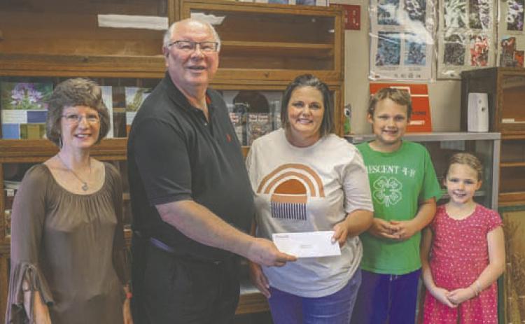 Central District four Trustee, Sid Sperry, presents 4-H Robotics Club leader Jennifer Dejonge; robotics club member Patrick Reinert, cloverbud member Jacqueline Reinert, and FCS/4H Educator Dawn Andrew with a grant from the Central Community Foundation.