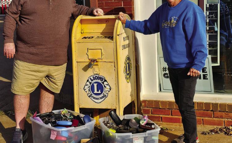 Guthrie Noon Lions Club members Troy Jenkins and Steve Gentling stand with the donation box located outside Vision Source in Guthrie, Oklahoma.