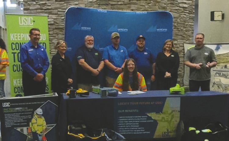 Owen Mallow signs his employment contract with USIC on April 15, 2026, at Meridian Technology Center during a ceremony attended by family, friends and company representatives. Mallow and classmates also received their assigned work vehicles following the signing. Photo submitted