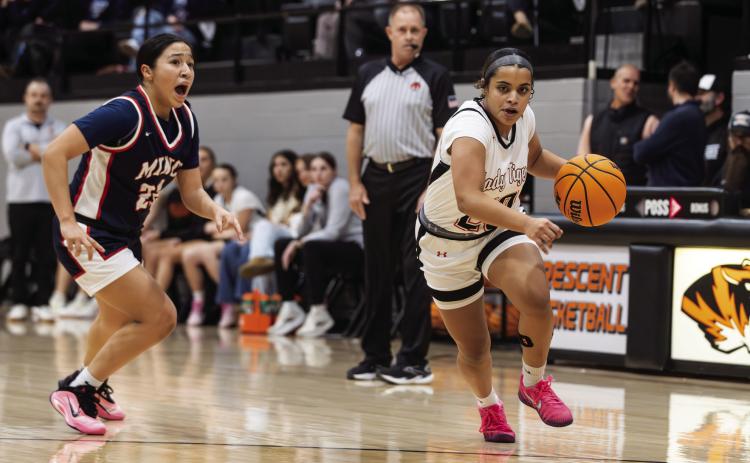 Aja Adams-House drives toward the basket during a girls basketball game as Minco closes in. Photo Brent Fuchs